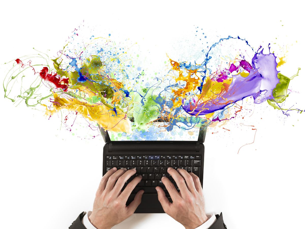 Splashes of colour coming from someone typing on laptop