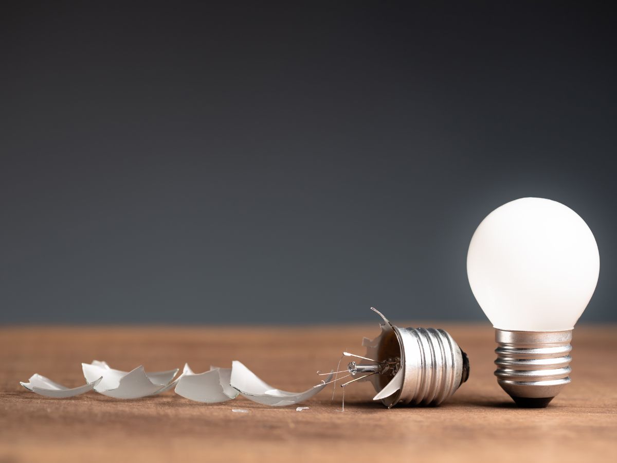 Broken light bulb next to a working light bulb